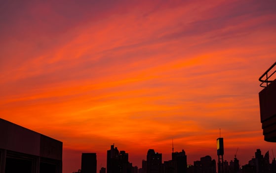 City building in the evening with beautiful red sunset sky and clouds. Urban landscape with red and orange sunset sky. Twilight with cityscape. Background quote for life after work all day. photo