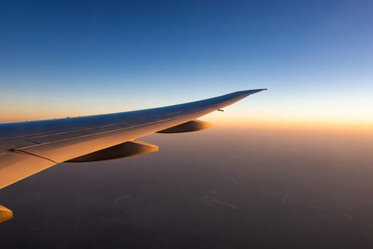 Wing of plane over the city. Airplane flying on blue sky. Scenic view from airplane window. Commercial airline flight in the morning with sunlight. Plane wing above clouds. Flight mechanics concept. photo