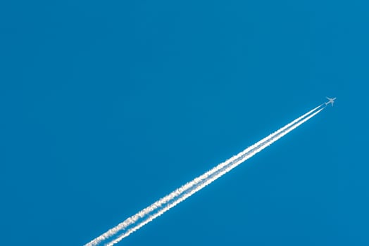 Airplane with white condensation tracks. Jet plane on clear blue sky with vapor trail. Travel by aeroplane concept. Trails of exhaust gas from airplane engine. Aircraft with white stripes. photo