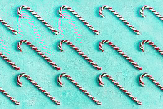 Christmas striped candy cane isolated on blue background. Candy cane pattern. Top view photo