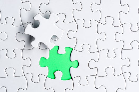 Piece of jigsaw puzzle on green paper. Flat lay, Directly above. photo