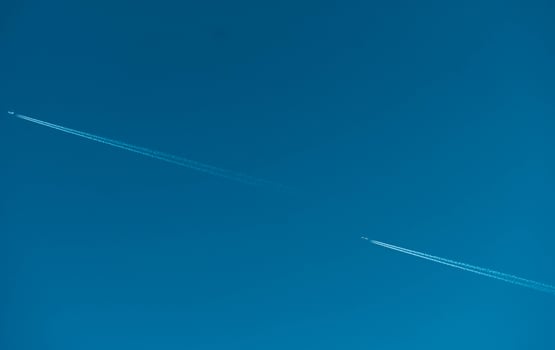 Two airplane with white condensation tracks. Jet plane on clear blue sky with vapor trail. Travel by aeroplane concept. Trails of exhaust gas from airplane engine. Aircraft with white stripes. photo