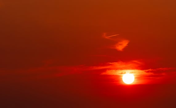 Beautiful red sun at sunset. Red sunset sky. The sun is obscured by some clouds at sunset. Big sun in the evening. Blood sky. Heat and hot weather. Dramatic sun light. Background for majestic. photo