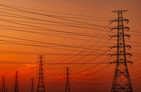 Silhouette high voltage electric pylon and electrical wire with an orange sky. Electricity poles at sunset. Power and energy concept. High voltage grid tower with wire cable at distribution station. photo