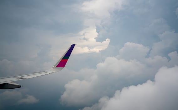 Wing of plane over the city. Airplane flying on blue sky. Scenic view from airplane window. Commercial airline flight in the morning with sunlight. Plane wing above clouds. Flight mechanics concept. photo