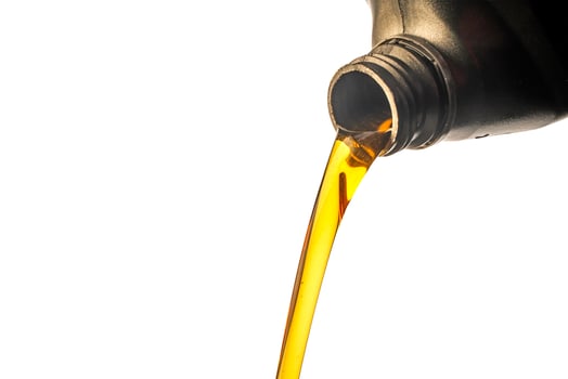 Car lubricant flows from gray bottle on isolated white background. photo