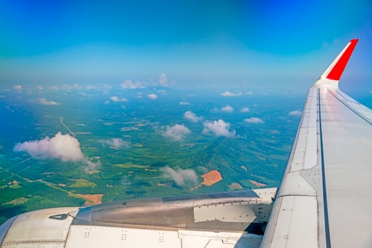 wings of airplanes during the flight look from the passenger window. There are white clouds in the blue sky. photo