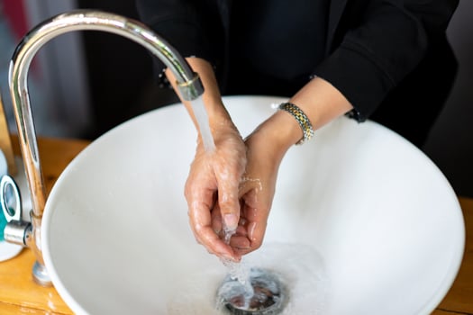 Business woman in dark black suit is washing her hand in sink. photo