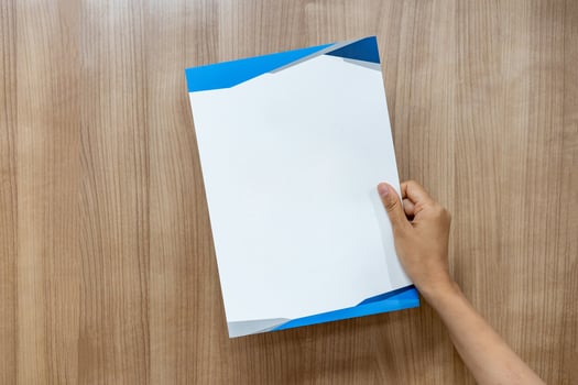 Asian person is holding and raising up the empty a4 paper on the wood background. photo