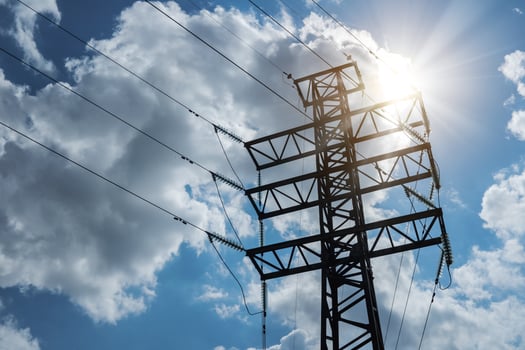 High-voltage electrical transmission corner tower against the background of a cloudy sky with sunbeams. photo