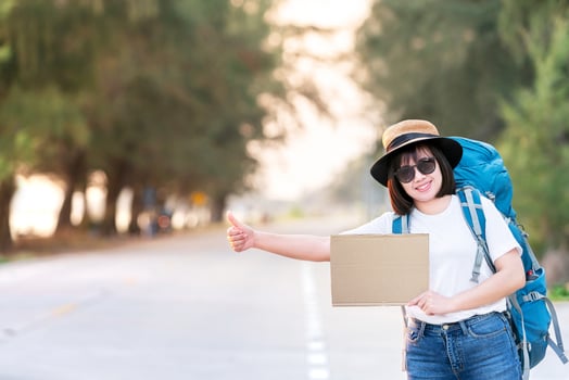 happy smile hitchhiker asian woman backpack waiting for car transportation during weekend for travel and journey trip in holiday at sunset time photo