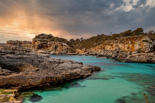 Beautiful view of blue sea and rocky cliffs against cloudy sky during sunset photo