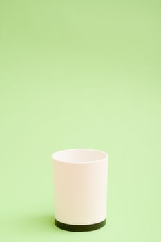 White plastic cup with a black bottom on green background. photo