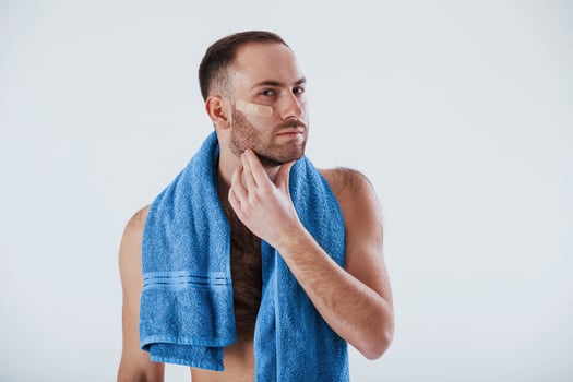 Nice clean skin. Man with blue towel stands against white background in the studio photo