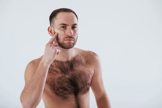 Showing on plaster by the hand. Man with bare chest stands against white background in the studio photo