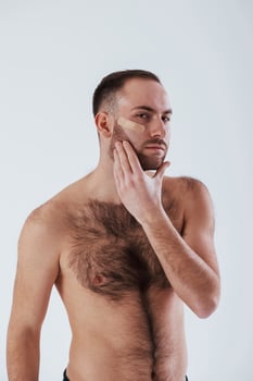 Results of shaving. Man with bare chest stands against white background in the studio photo