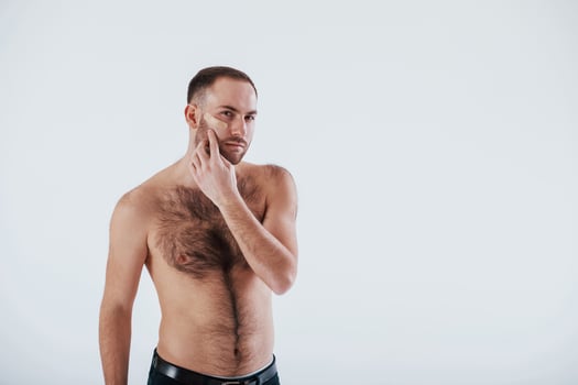 Serious guy at the morning time. Man with bare chest stands against white background in the studio photo