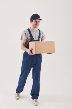 Walking in front of him. Guy with box in hands stands against white background in the studio photo