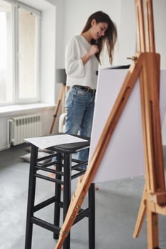 Plan of the building lying on the black chair. Young brunette in the room with white walls and daylight that comes from the window photo
