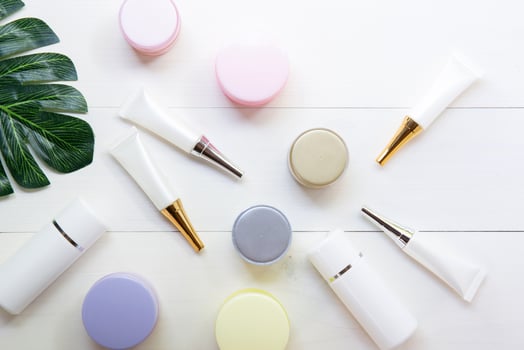 cosmetic and skin care product and green leaves on white wood table, beauty with treatment cream and moisturizing on wooden desk, health and wellness concept, top view. photo