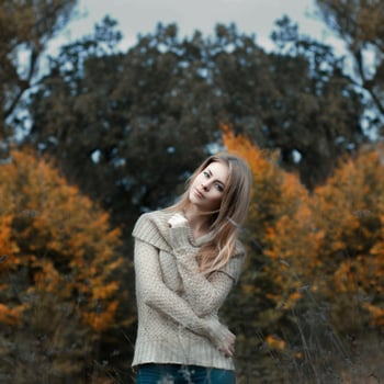 Girl in a sweater standing in a field photo