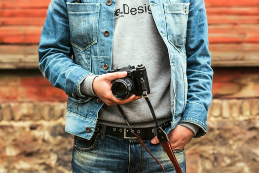 Stylish hipster photographer in fancy denim clothes holding a camera photo