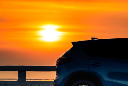 Blue compact SUV car with sport and modern design parked on concrete road by the sea at sunset in the evening. Hybrid and electric car technology concept. Car parking space. Automotive industry. photo