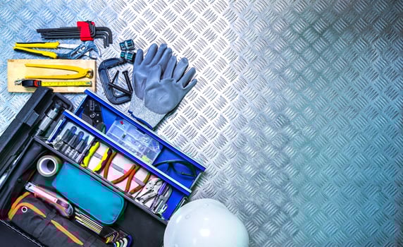 Top view of tools box and helmet on checkered plate background in workshop. Service tools set. Home building and electrical tools. Plumber hand tools. Technician equipment for repair work. photo