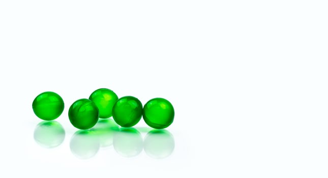 Five green round soft capsule pills isolated on white background with copy space. Ayurvedic medicine for indigestion, gas and acidity. Herbal medicine made from Mentha oil and spearmint oil from India photo