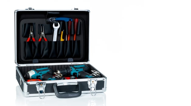 Toolbox isolated on white background. Black toolbox with tools. Pliers, spanner or wrench, screwdriver, cutter, and cordless driver drill in tool case. Toolkit of handyman. Mechanic hand tools. photo