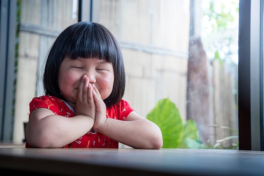 Happy little girl praying at home, child's pure faith, focus at face. photo