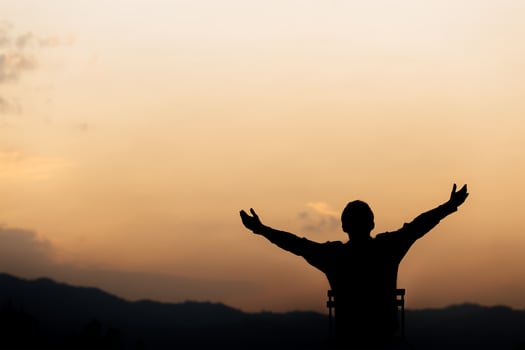 Silhouette of a man lift hands up and prayer and worship God at sunset. concept of religion. photo