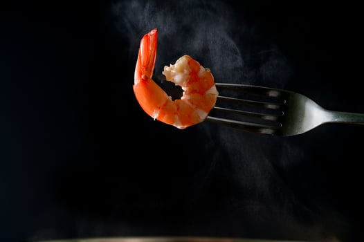 Steamed shrimp on fork isolated on dark background with copy space. Seafood buffet in restaurant concept. Use for seafood buffet promotions advertising photo