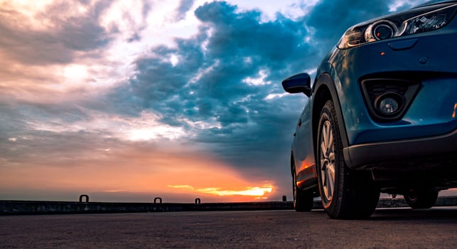 Blue compact SUV car with sport and modern design parked on concrete road by the sea at sunset in the evening. Hybrid and electric car technology concept. Car parking space. Automotive industry. photo