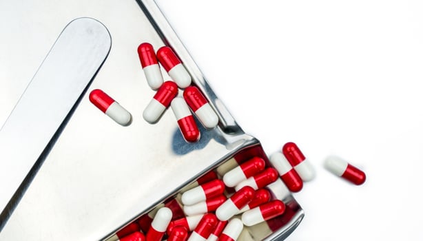 Top view of red-white antibiotic capsule pills on stainless steel drug tray. Antibiotc drug resistance. Prescription drugs. Pharmaceutical industry. photo