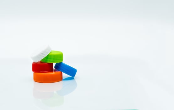 Pile of different size of white, green, red, blue and orange color round plastic screw caps on white background and copy space. photo