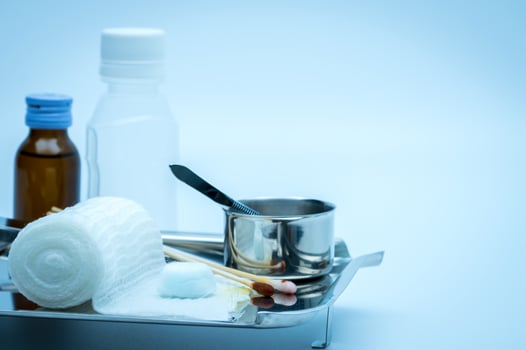 Wound care dressing set on stainless steel plate. Cotton ball with alcohol, cotton stick with povidone-iodine, forceps and conform bandage. photo