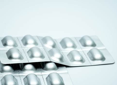 Tablet pills in silver aluminium blister pack packaging on blurred background of pack of pills with copy space photo