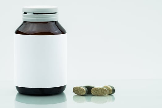 Vitamins, supplements and minerals dual layer tablets pills and medicine amber glass bottle with blank label isolated on white background with copy space. Use for vitamins and supplements advertising. photo
