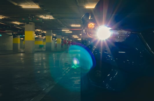 SUV car open headlight light and parked at underground car parking of shopping. Parking lot of shopping mall in the evening. Car parked lonely at night. Car thief at mall concept. photo