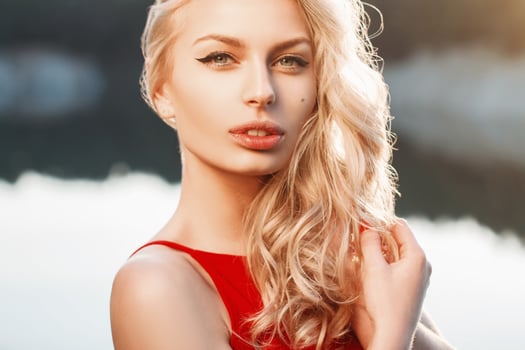 Close-up portrait of a beautiful woman with red dress on the background of the sea. Sunset light photo