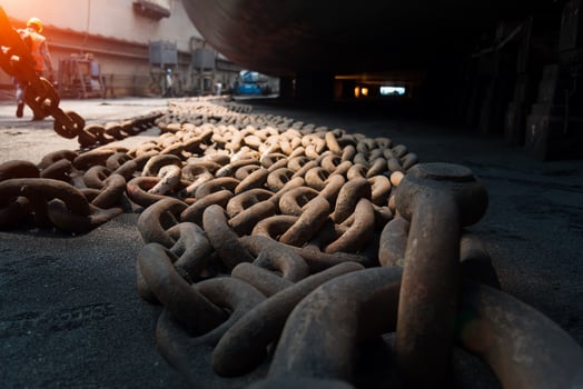 Close up view of big metal anchor chain of cargo ship in dry dock for repairs and painting in shipyard photo