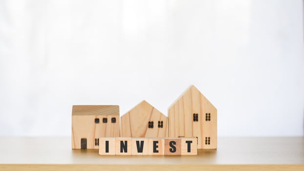Real estate investment concept. Wooden block with text invest and model houses, real estate growth in the future, finance, banking, lending, and trading. photo