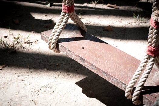 A wooden swing with twine tied to a tree photo