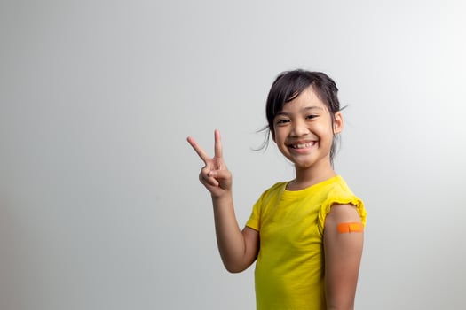 COVID 19 Vaccines for Kids concept. Studio a portrait of an adorable Asian girl after getting his first dose of vaccine. Immune, Safe, Available, Back to school. photo