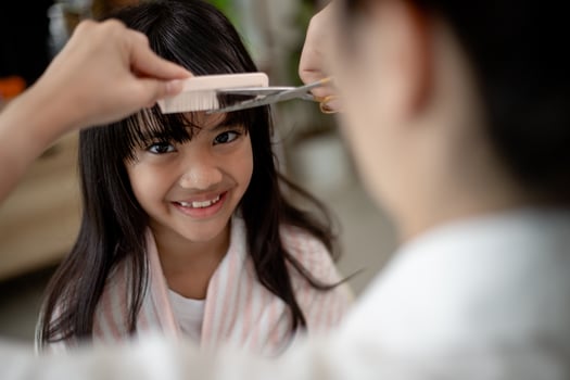 Asian Mother cutting hair to her daughter in living room at home while stay at home safe from Covid-19 Coronavirus during lockdown. Self-quarantine and social distancing concept. photo
