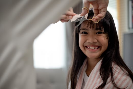 Asian Mother cutting hair to her daughter in living room at home while stay at home safe from Covid-19 Coronavirus during lockdown. Self-quarantine and social distancing concept. photo