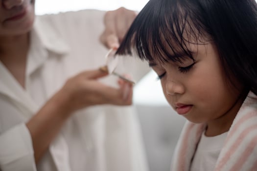 Asian Mother cutting hair to her daughter in living room at home while stay at home safe from Covid-19 Coronavirus during lockdown. Self-quarantine and social distancing concept. photo