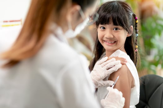 Vaccination concept. Female doctor vaccinating cute little girl in clinic photo