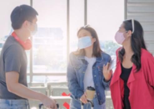 Soft blur background of young asian traveler friend group wearing protective face mask enjoy chatting together at airport terminal station. Light effect. photo